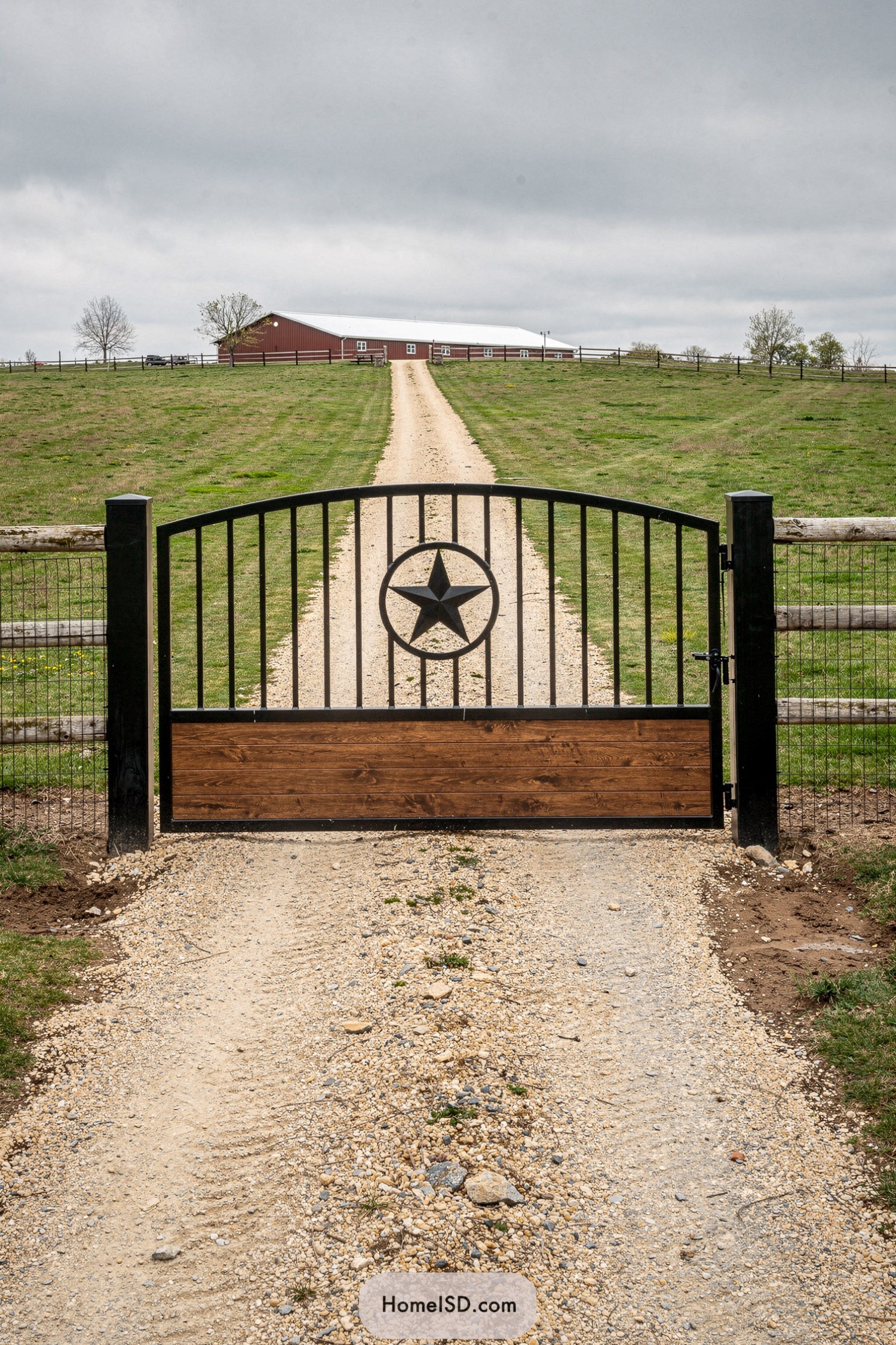 Black metal ranch gate with central star emblem and wood panel base