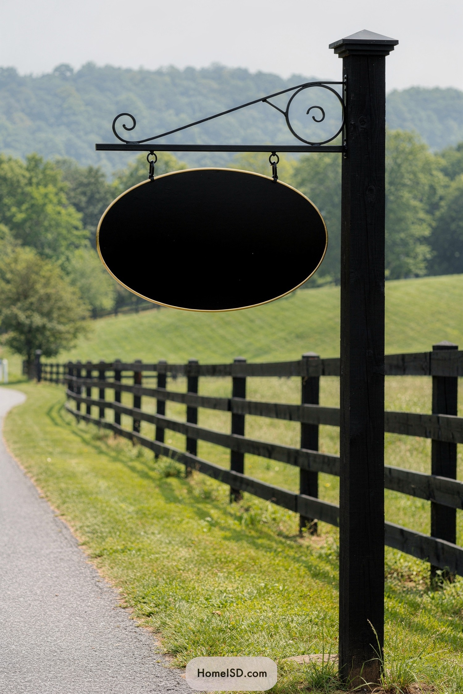Black oval hanging farm sign on tall black post beside rural driveway