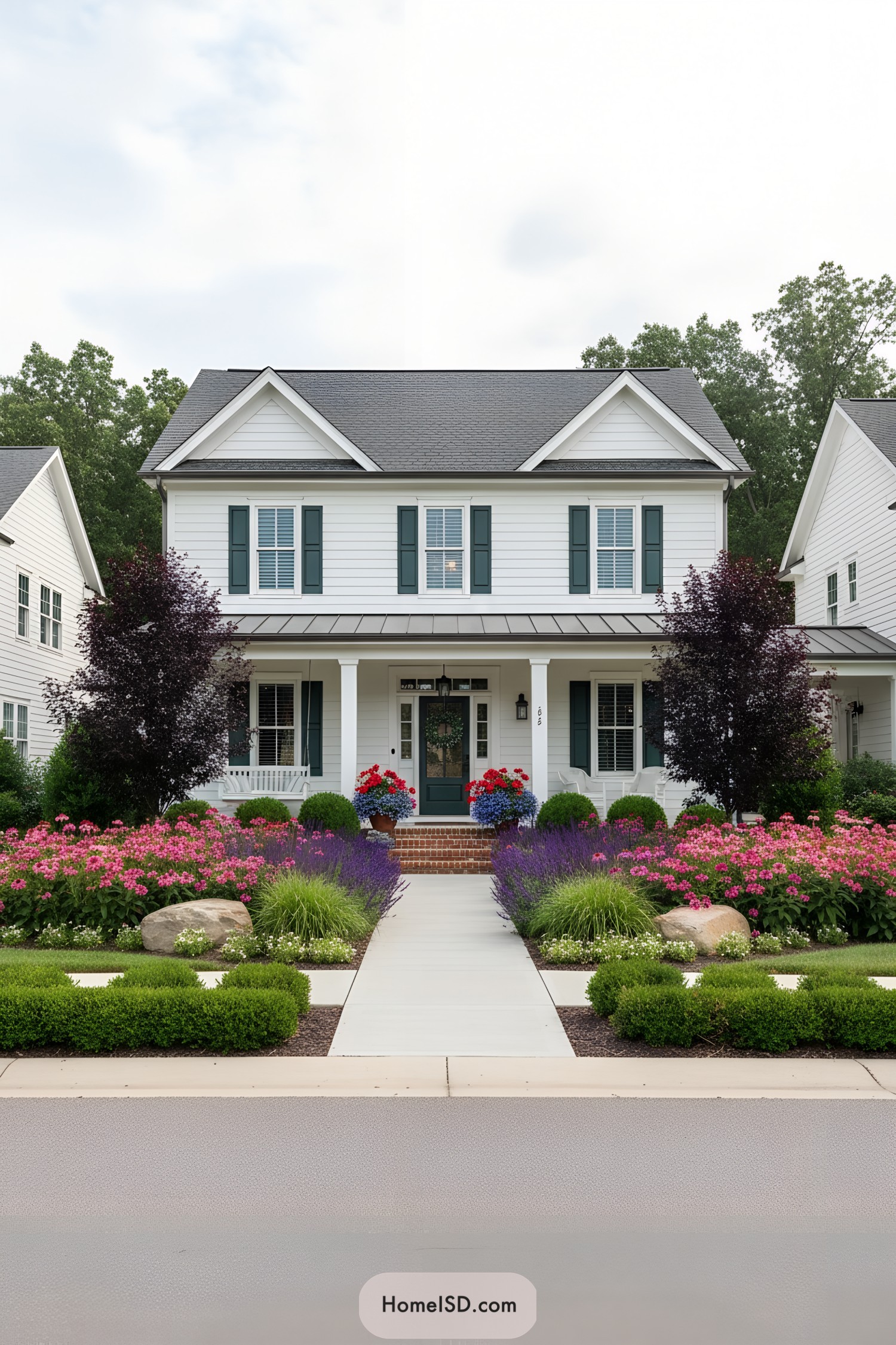 White farmhouse with colorful flower beds and central path leading to front porch