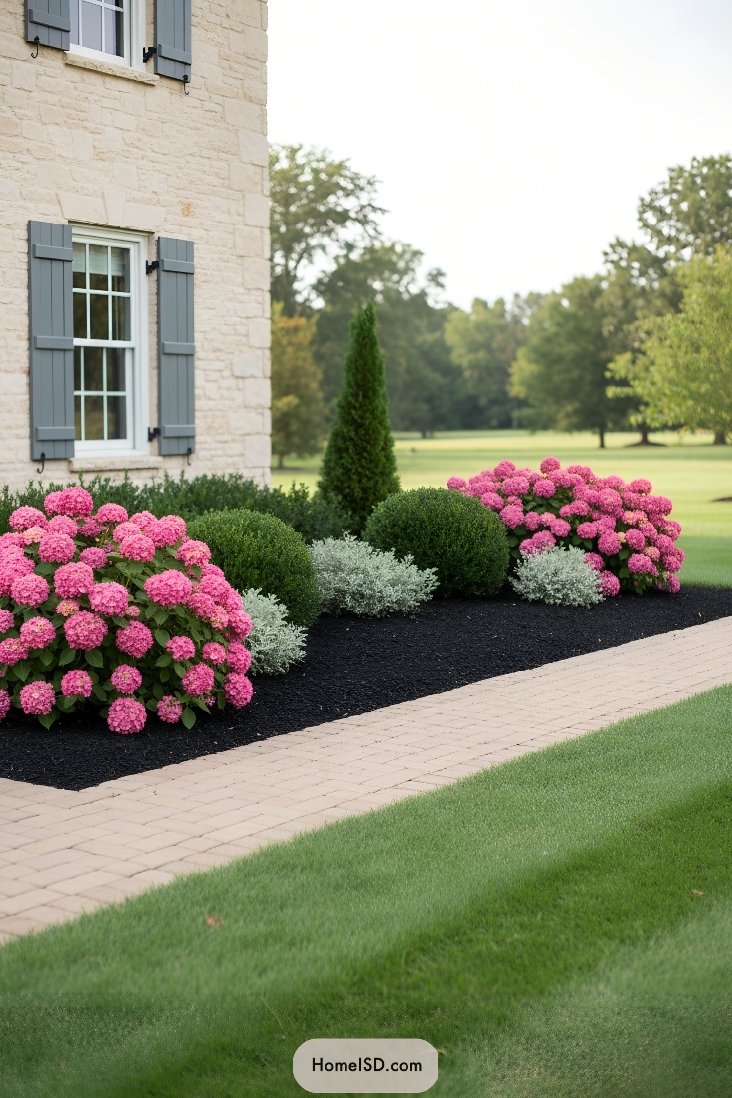 Front garden with pink hydrangeas and boxwoods along a stone house