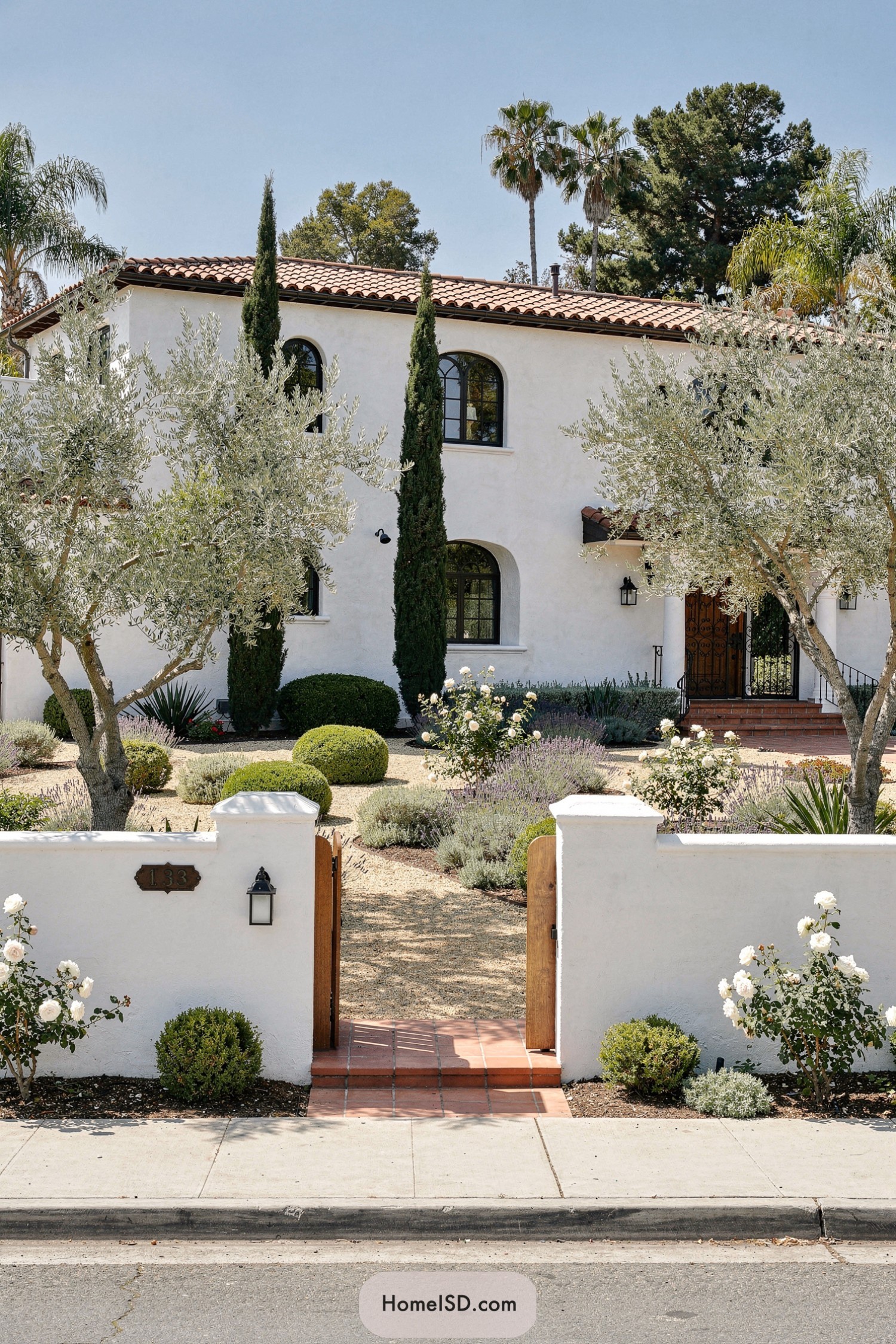 Spanish style stucco house with terracotta roof and drought tolerant front garden of olives lavender and clipped shrubs