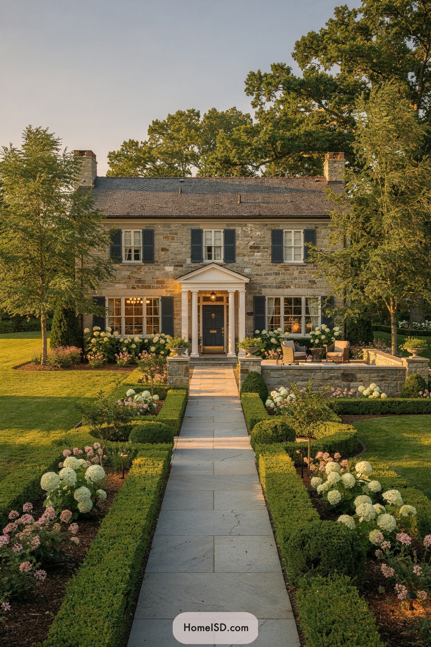 Formal stone house with boxwood-lined entry path