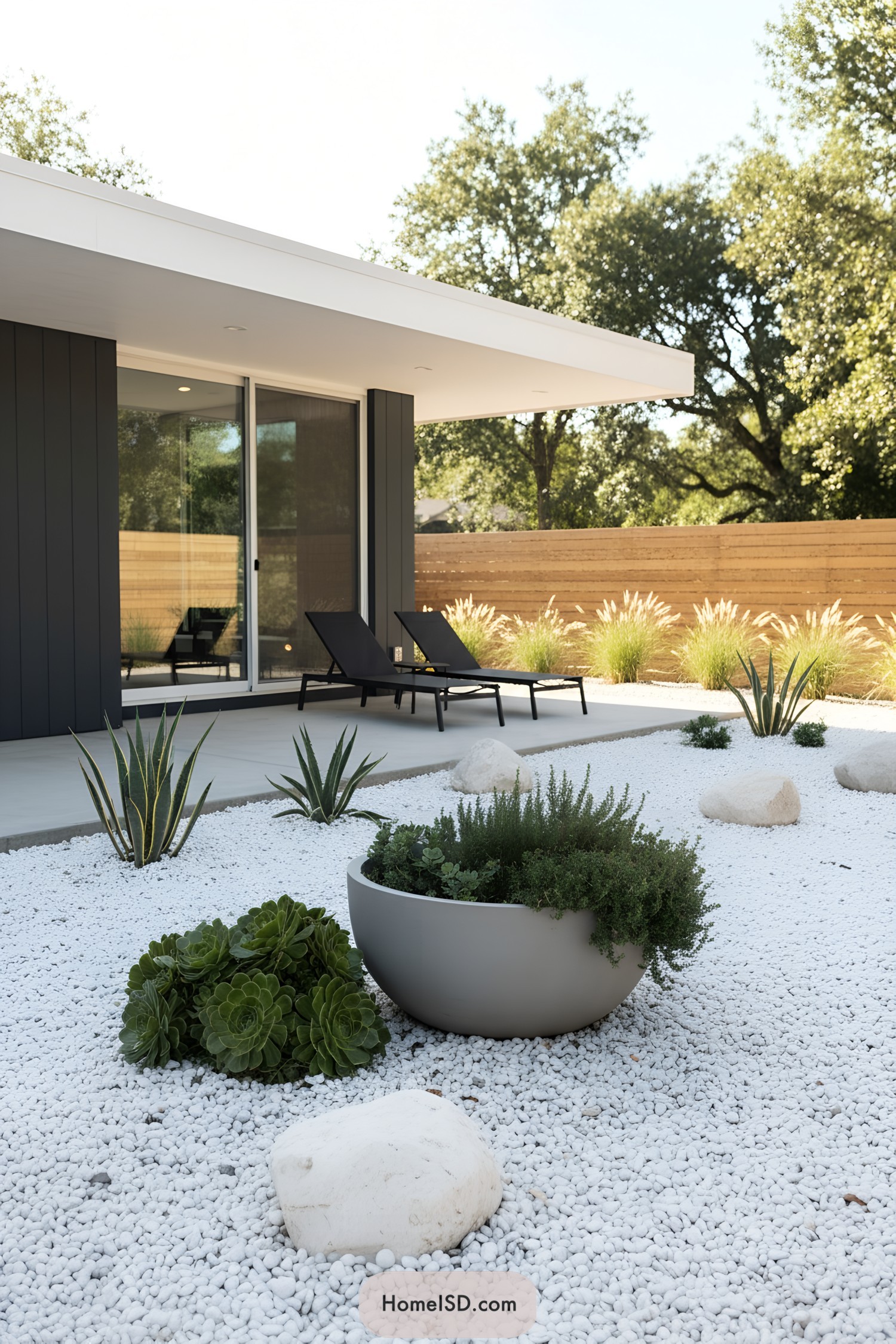 Modern patio with white pebble garden, succulents, and black loungers